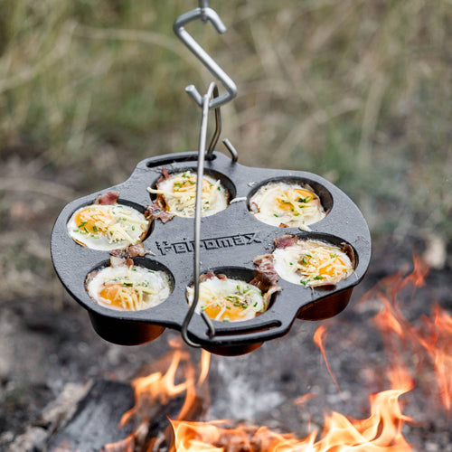 Heavy-duty cast iron muffin pan with six compartments cooking eggs topped with cheese and herbs suspended over an open fire, ideal for Farm, Garden & Tool, Camping, Kitchen & Food, Cast Iron, and Cookware collections.