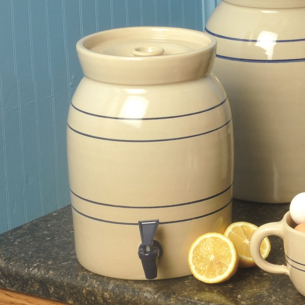 Handcrafted cream stoneware beverage cooler with classic blue stripes and dark blue spigot, made in USA, shown on kitchen countertop with lemon halves, fits Kitchen & Food and Storage and Serving collections.