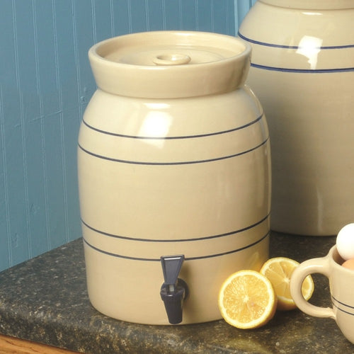 Handcrafted cream stoneware beverage cooler with classic blue stripes and dark blue spigot, made in USA, shown on kitchen countertop with lemon halves, fits Kitchen & Food and Storage and Serving collections.
