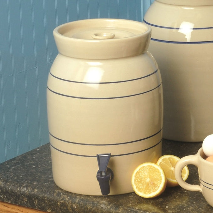 Handcrafted cream stoneware beverage cooler with classic blue stripes and dark blue spigot, made in USA, shown on kitchen countertop with lemon halves, fits Kitchen & Food and Storage and Serving collections.