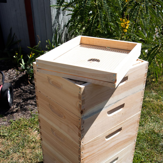 Handcrafted wooden 10-frame candy board feeder made in the USA, placed on top of a stacked beehive outdoors, part of Farm, Garden & Tool and Amish Made collections.