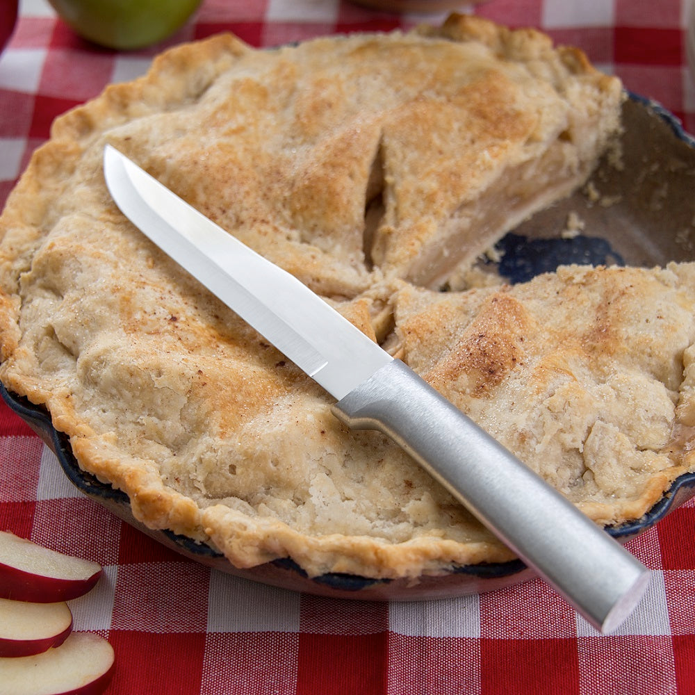 Handcrafted Rada Stubby Butcher Knife with a stainless steel blade and silver brushed aluminum handle resting on a rustic apple pie, suitable for Kitchen & Food, Food Prep, and USA Made collections.
