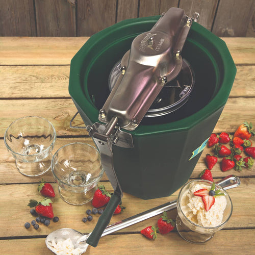 Handcrafted Amish-made green ice cream freezer with polished stainless steel crank mechanism, surrounded by fresh strawberries, blueberries, and glass bowls in kitchen specialty equipment collection.