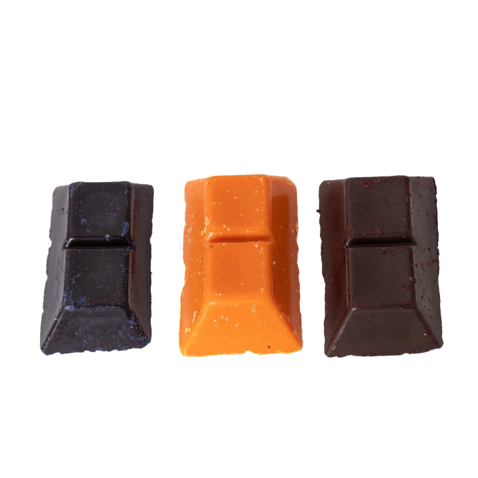Three handcrafted soy wax dye chips in dark brown, bright orange, and deep red colors, designed for use in candle making supplies collections.