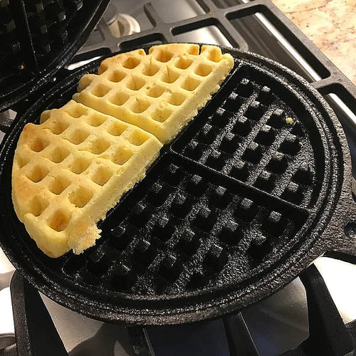 Half-cooked round waffle inside a handcrafted pre-seasoned stovetop cast iron waffle maker on a gas stove, featured in Farm, Garden & Tool, Kitchen & Food, and Cast Iron collections.