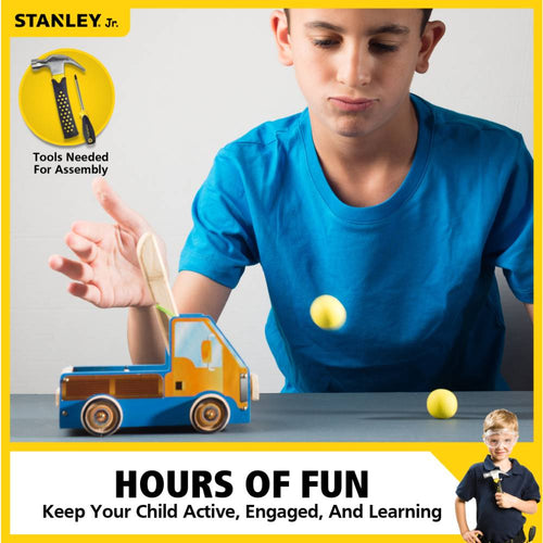 Young boy in blue shirt launching yellow foam ball with a handcrafted wooden truck catapult, ideal for creative play and learning in indoor arts and crafts collections.
