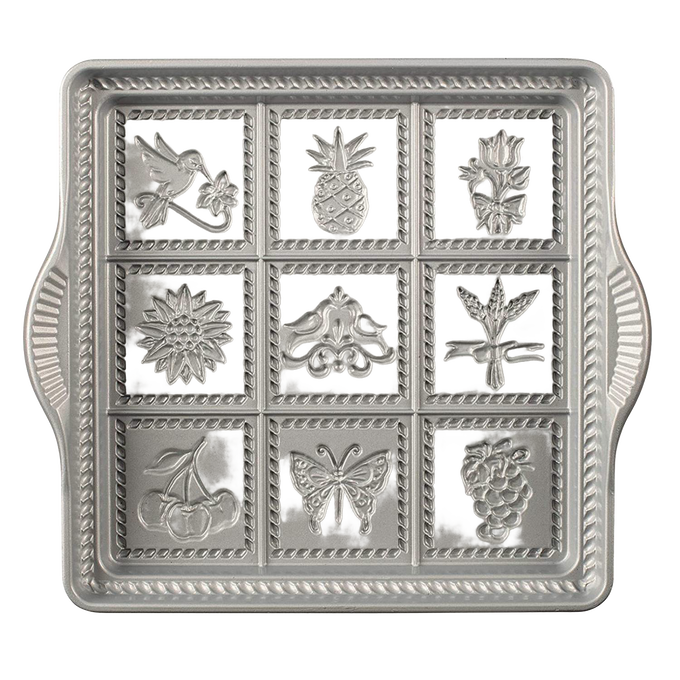 Cast aluminum baking pan with decorative embossed designs including bird, pineapple, flower, and butterfly, featuring rope borders, handcrafted in USA, ideal for kitchen and baking supplies collections.