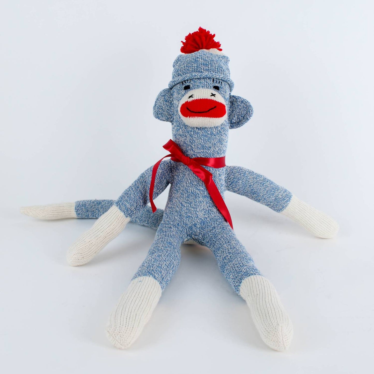 Handcrafted blue and white hand-sewn sock monkey wearing a red pom-pom hat and ribbon bow, made in USA, featured in Toys, Books & Games, Children's Toys, Indoor Play, and Best Sellers collections.