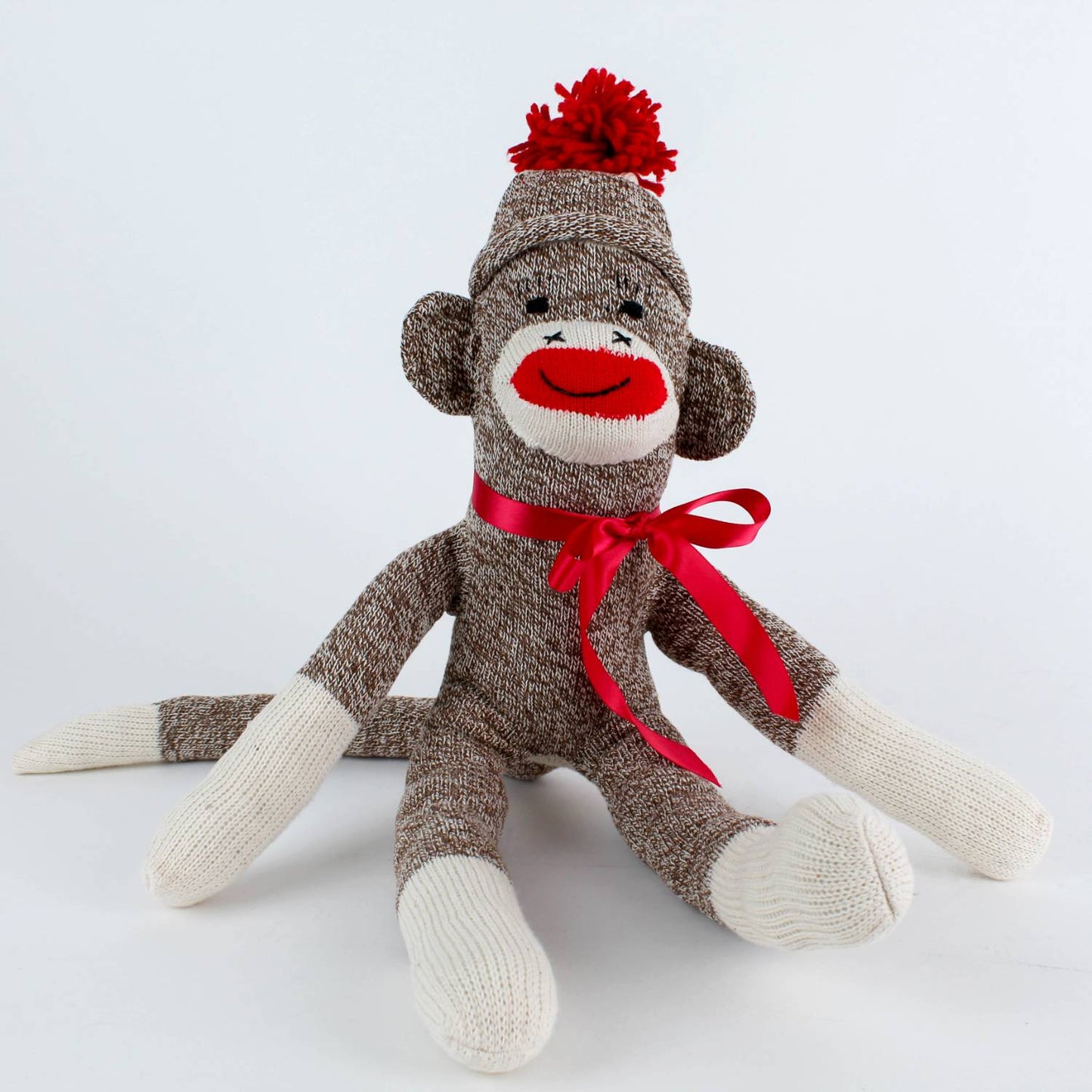 Handcrafted brown and cream sock monkey with red pom-pom hat and ribbon, made in USA, featured in Toys, Books & Games, Children’s Toys, Indoor Play, and Best Sellers collections.