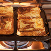 Seasoned cast iron reversible grill and griddle pan cooking french toast on a stovetop burner, handcrafted in USA, ideal for Kitchen & Food, Cast Iron, Cookware, and Best Sellers collections.