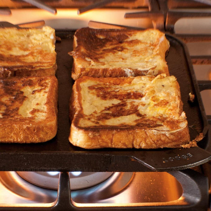 Seasoned cast iron reversible grill and griddle pan cooking french toast on a stovetop burner, handcrafted in USA, ideal for Kitchen & Food, Cast Iron, Cookware, and Best Sellers collections.
