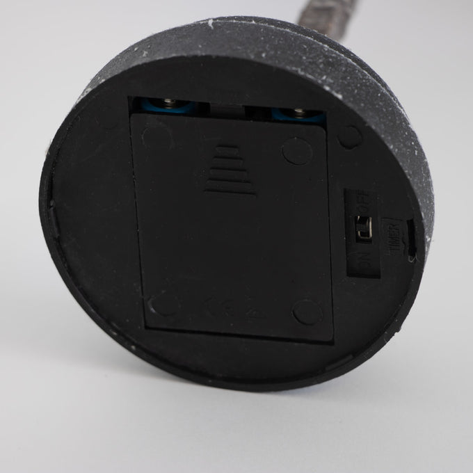 Close-up of a black round battery compartment with a slide cover and on/off switch, part of a handcrafted lighted holiday tree for Home & Decor, Holiday Decor, Best Sellers, and Promo Eligible collections.
