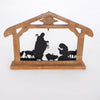 Wooden nativity display with metal silhouettes of the Holy Family and animals in a weathered stable, featuring a vintage style for Home & Decor and Holiday collections.