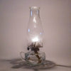 Handcrafted clear glass oil lamp with unique finger hold on the side, lit with warm flame, ideal for lamps & lighting, oil lamps, table lamps, and best sellers collections.
