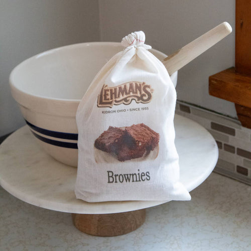 Cloth bag of Lehman's Brownie Mix with a wooden scoop, displayed on a marble cake stand in a kitchen setting, part of Kitchen & Food, Pantry, and USA Made collections.