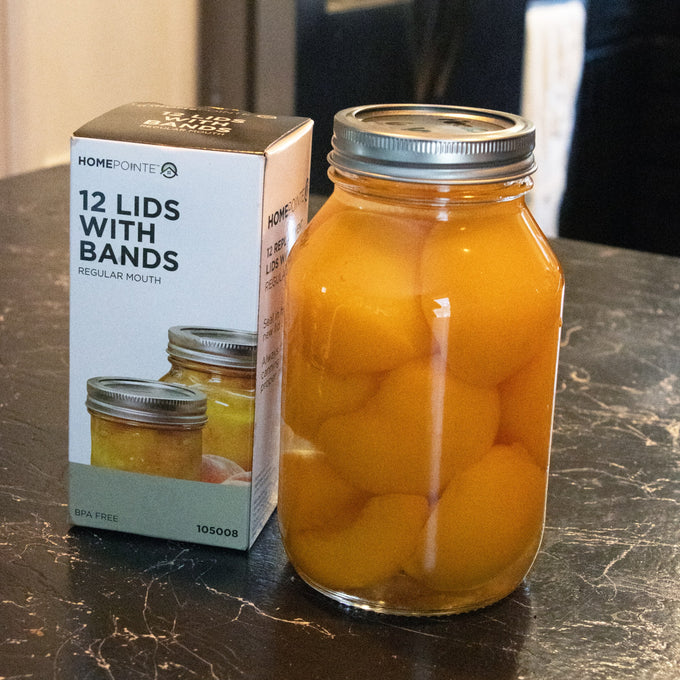 Box of 12 regular-mouth jar lids with BPA-free bands displayed next to a glass jar filled with preserved peaches, ideal for Kitchen & Food, Food Preservation, and Canning collections.