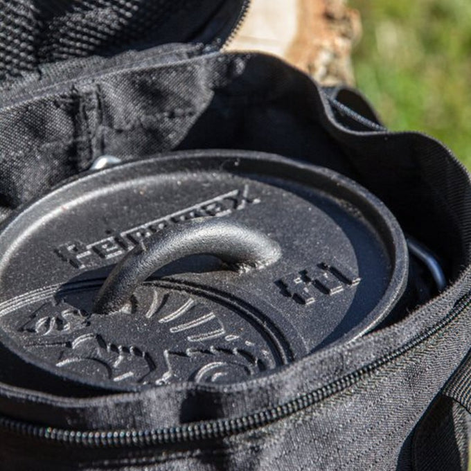 Close-up of a black cast iron Dutch oven lid with embossed logo inside a partially open durable black transport bag, ideal for Farm, Garden & Tool, Camping, Best Sellers, and Promo Eligible collections.