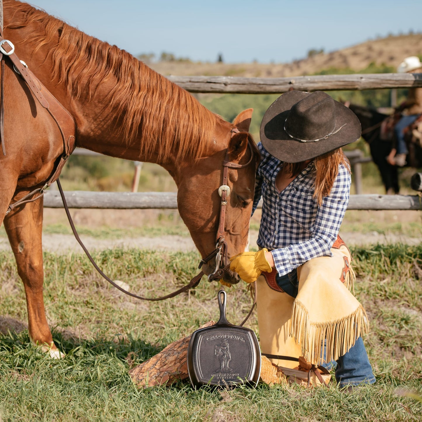Handcrafted cast iron grill pan with an embossed cowboy design, made in USA, displayed outdoors next to a horse and rider in western attire, fitting Kitchen & Food and Cast Iron collections.