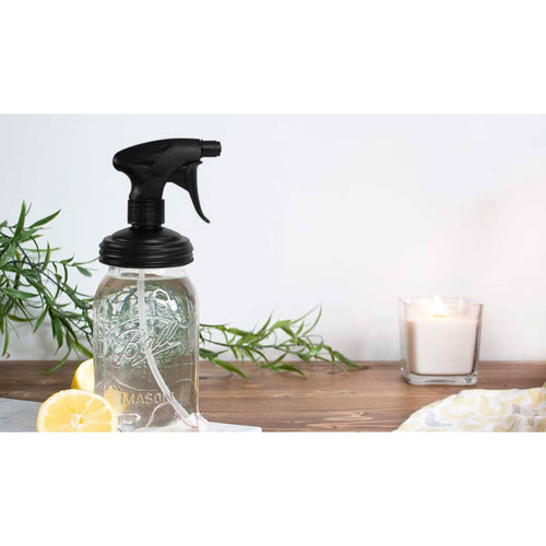 Black plastic sprayer lid fitting a regular-mouth glass Mason jar with silicone gasket, styled on a wooden surface with lemon halves, greenery, and a lit candle, ideal for Home & Decor, Household Helpers, USA Made, Best Sellers collections.