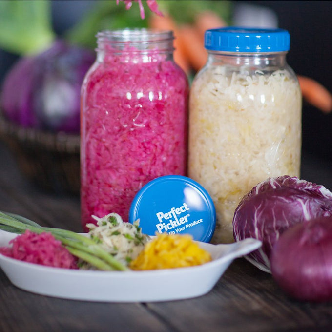 Handcrafted fermenting jars with blue lids containing vibrant homemade pickled vegetables, displayed alongside fresh cabbage and assorted colorful pickled produce, suitable for Kitchen & Food, Food Preservation, Fermenting and Pickling, Kitchen Gadgets, Cooking and Baking Helpers, USA Made, Best Sellers, and Promo Eligible collections.