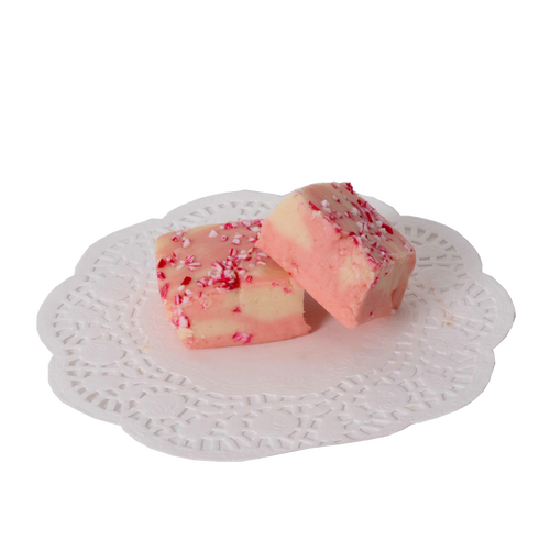 Two handcrafted peppermint fudge pieces with creamy white and pink swirls topped with crushed candy, displayed on a decorative white paper doily, part of Kitchen & Food and USA Made collections.