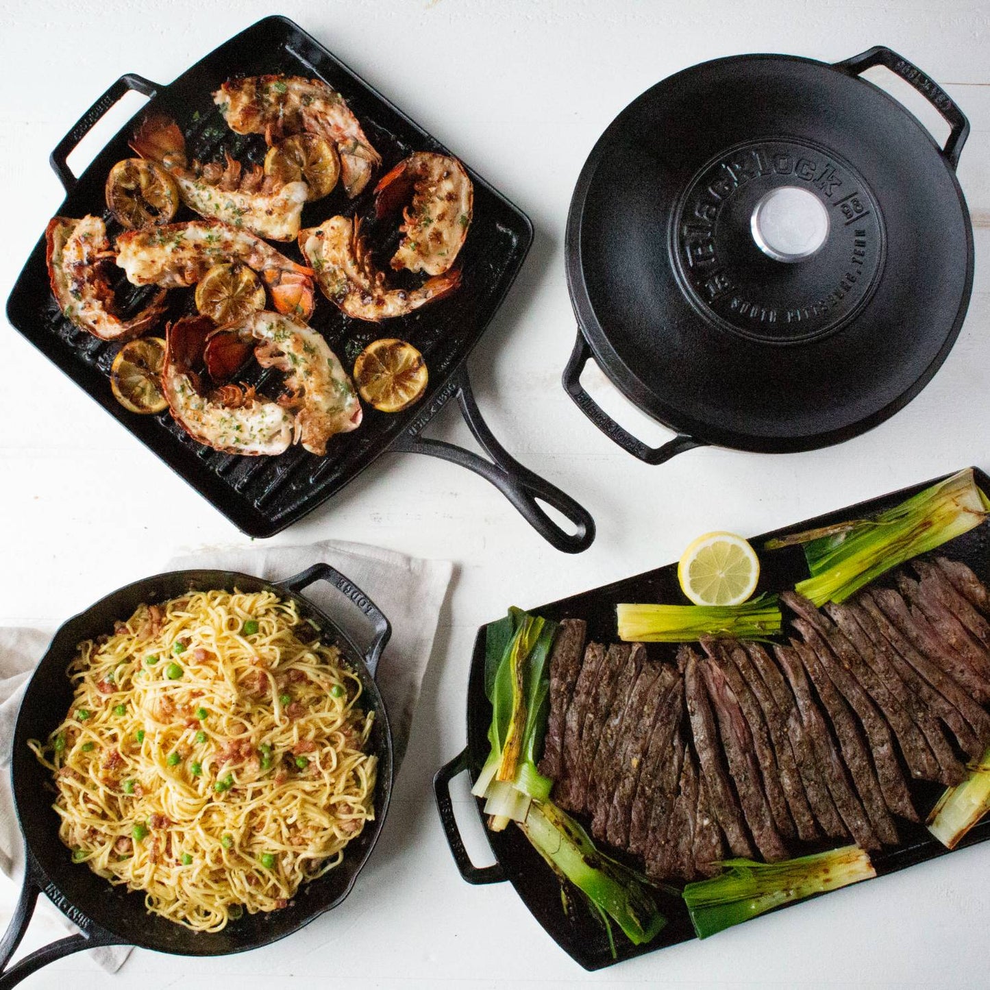 Assortment of cast iron cookware including a skillet with cooked noodles, a grill pan with grilled seafood and lemon slices, a griddle with sliced steak and green onions, and a seasoned cast iron lid, featured in Kitchen & Food, Cookware, Cast Iron, USA Made, and Best Sellers collections.