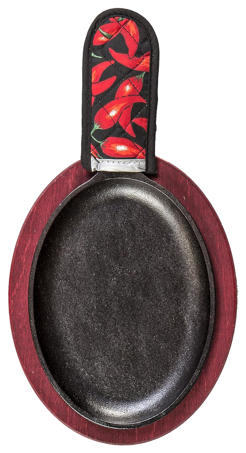 Oval cast iron griddle with a deep black cooking surface, set on a red stained wooden underliner and topped with a chili pepper patterned handle holder, ideal for camping and cookware collections.