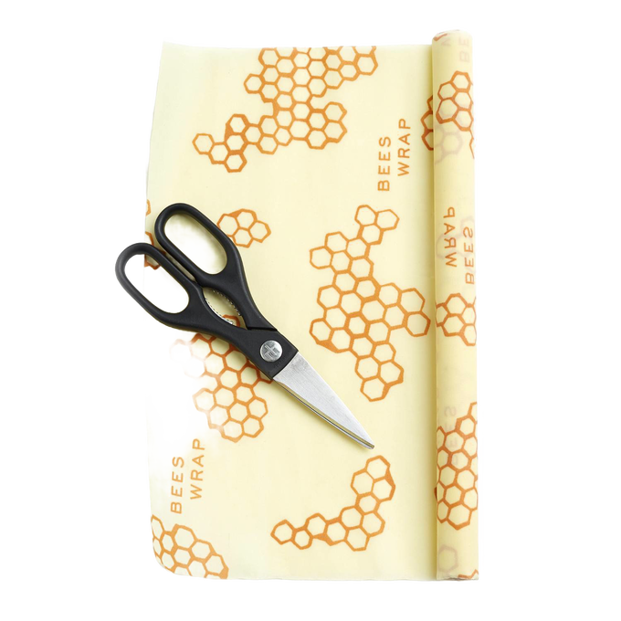 Partially unrolled beeswax food wrap with honeycomb pattern and printed text, accompanied by black-handled scissors, handcrafted in the USA for Kitchen & Food and Storage and Serving collections.
