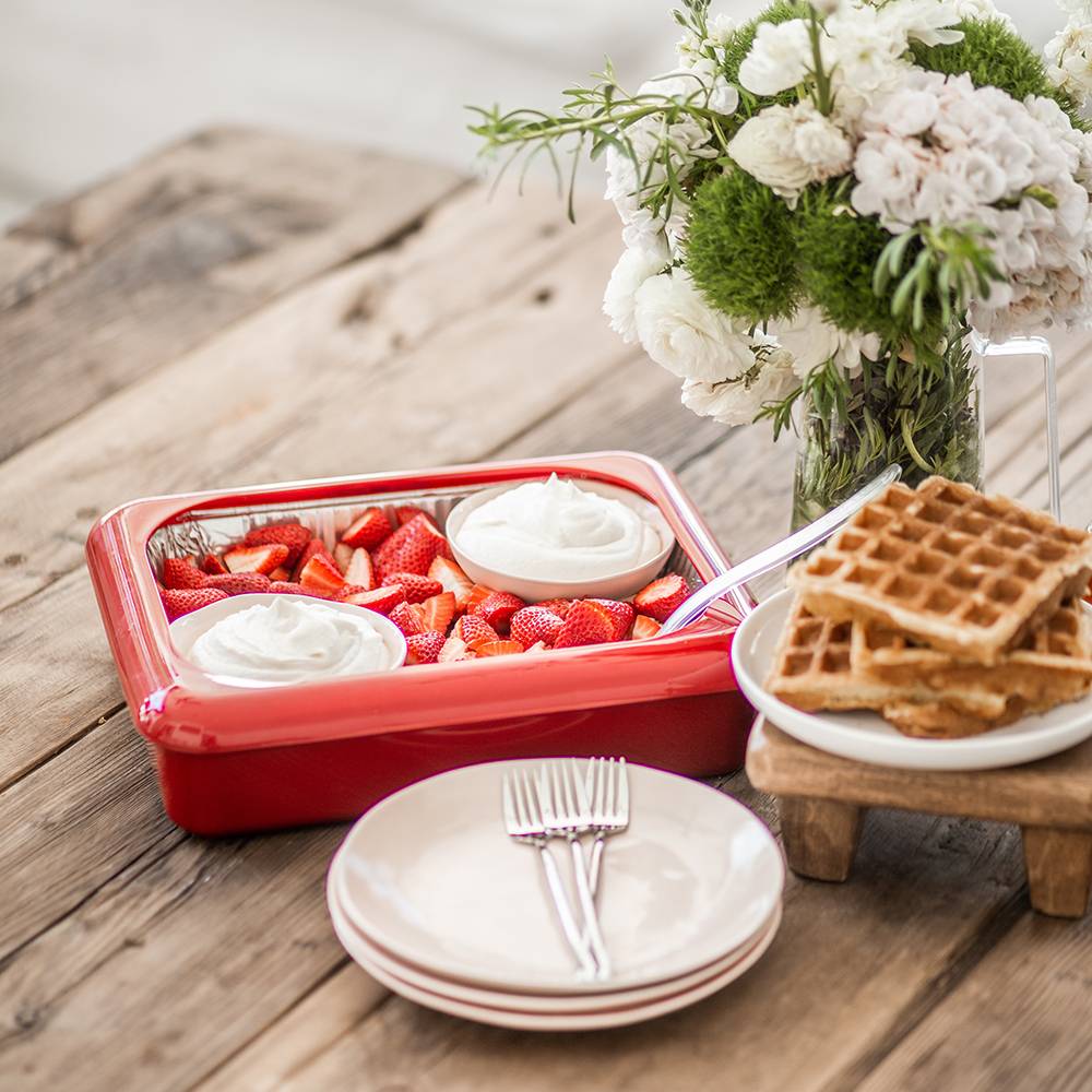 Red Fancy Panz foil pan cover enclosing fresh sliced strawberries with two dollops of whipped cream, set on a rustic wood table with stacked plates, forks, waffles, and a floral vase, ideal for Kitchen & Food, Kitchen Gadgets, Storage and Serving, USA Made, and Best Sellers collections.