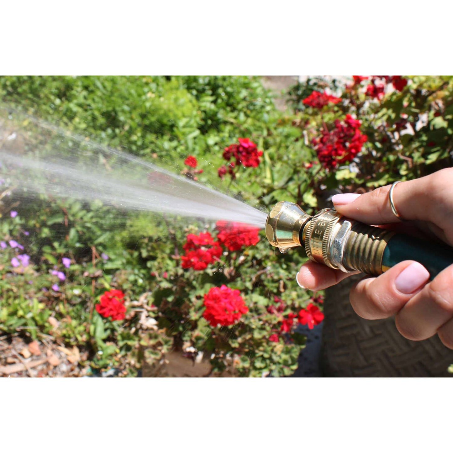 Handheld brass garden hose nozzle delivering a strong, efficient water stream to vibrant red flowers, featured in Farm, Garden & Tool, Garden Accessories, Lawncare, USA Made, and Best Sellers collections.