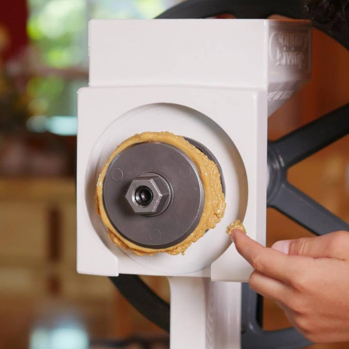 Close-up view of a handcrafted peanut butter accessory attached to a grain mill, with smooth fresh peanut butter being spread by hand, featured in Kitchen & Food, Grain Mills, USA Made, and Best Sellers collections.