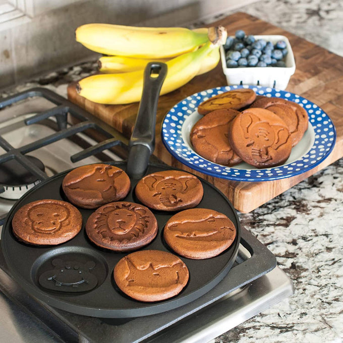 Cast aluminum pancake pan featuring seven animal-shaped molds including monkey, lion, and alligator, with freshly cooked pancakes on a kitchen stove, perfect for Kitchen & Food, Cookware, Baking Supplies, Pots and Pans, and USA Made collections.