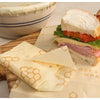Set of three handmade beeswax food wraps with honeycomb pattern, eco-friendly alternative for food storage, displayed with sandwich and covered bowl, part of Kitchen & Food and USA Made collections.