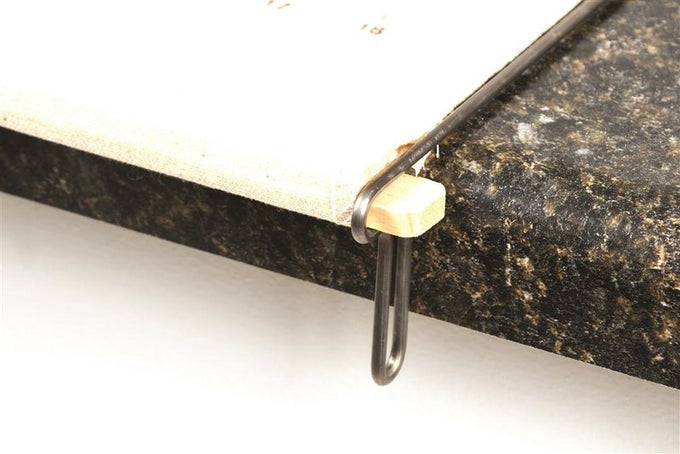 Close-up of wooden slat and long metal loop securing a fabric pastry frame taut on a dark countertop, crafted for Kitchen & Food, Cookware, Baking Supplies, Best Sellers, and Promo Eligible collections.