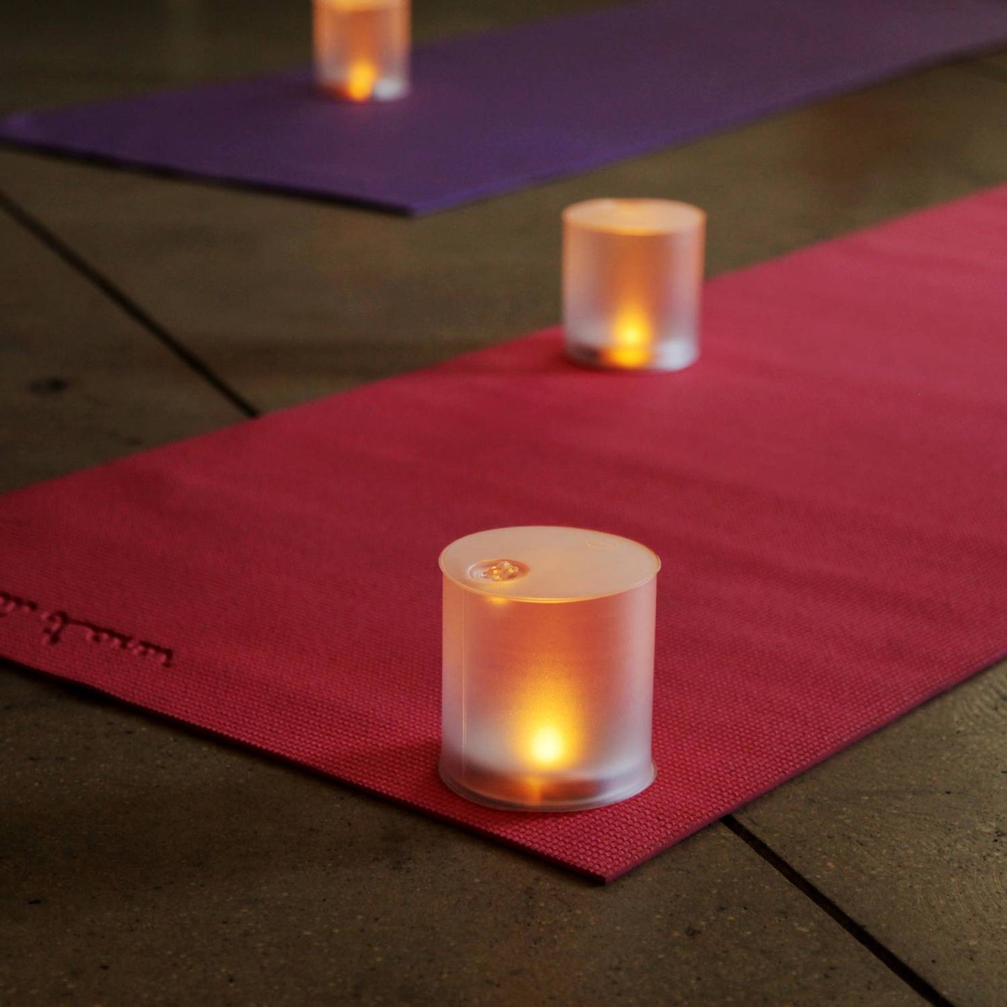 Soft glowing inflatable solar LED candle on a red yoga mat, emitting warm flickering light for safe ambiance during indoor relaxation, camping, or emergency use.