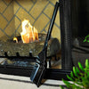 Black metal ash shovel with ergonomic handle leaning against a fireplace screen in front of a burning wood stove, handcrafted in USA, featured in Hearth Accessories and Stoves collections.