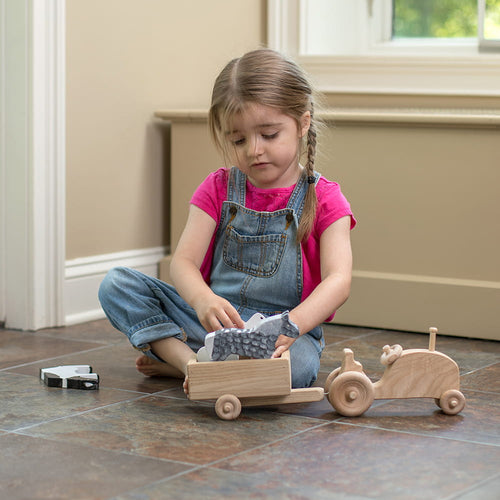 Young child playing indoors with handcrafted Amish-made wooden tractor and trailer toy set, featured in Toys, Books & Games, USA Made, Amish Made, and Children's Toys collections.