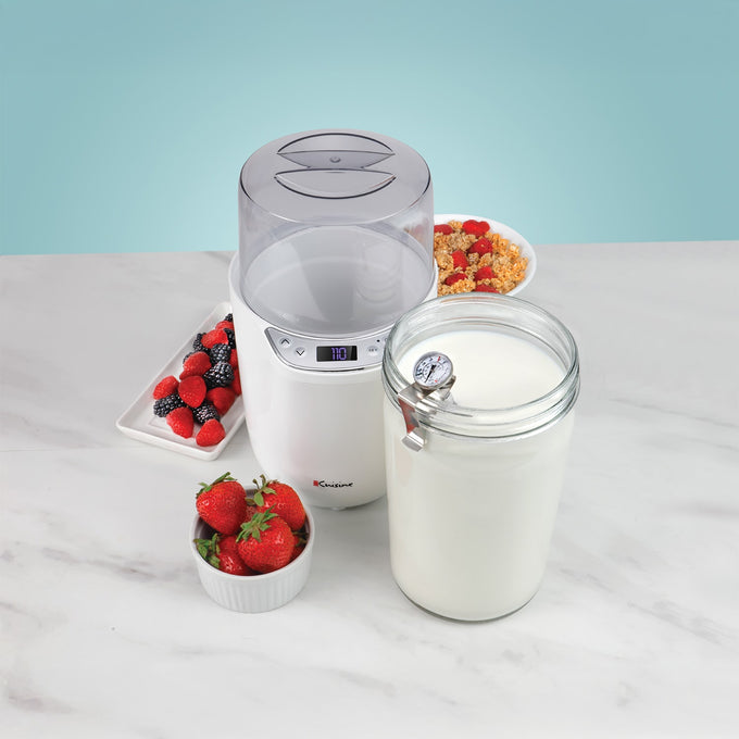 Compact white electric yogurt and Greek yogurt maker with clear lid, accompanied by a glass jar with temperature gauge and fresh berries, featured in kitchen and specialty equipment collections.