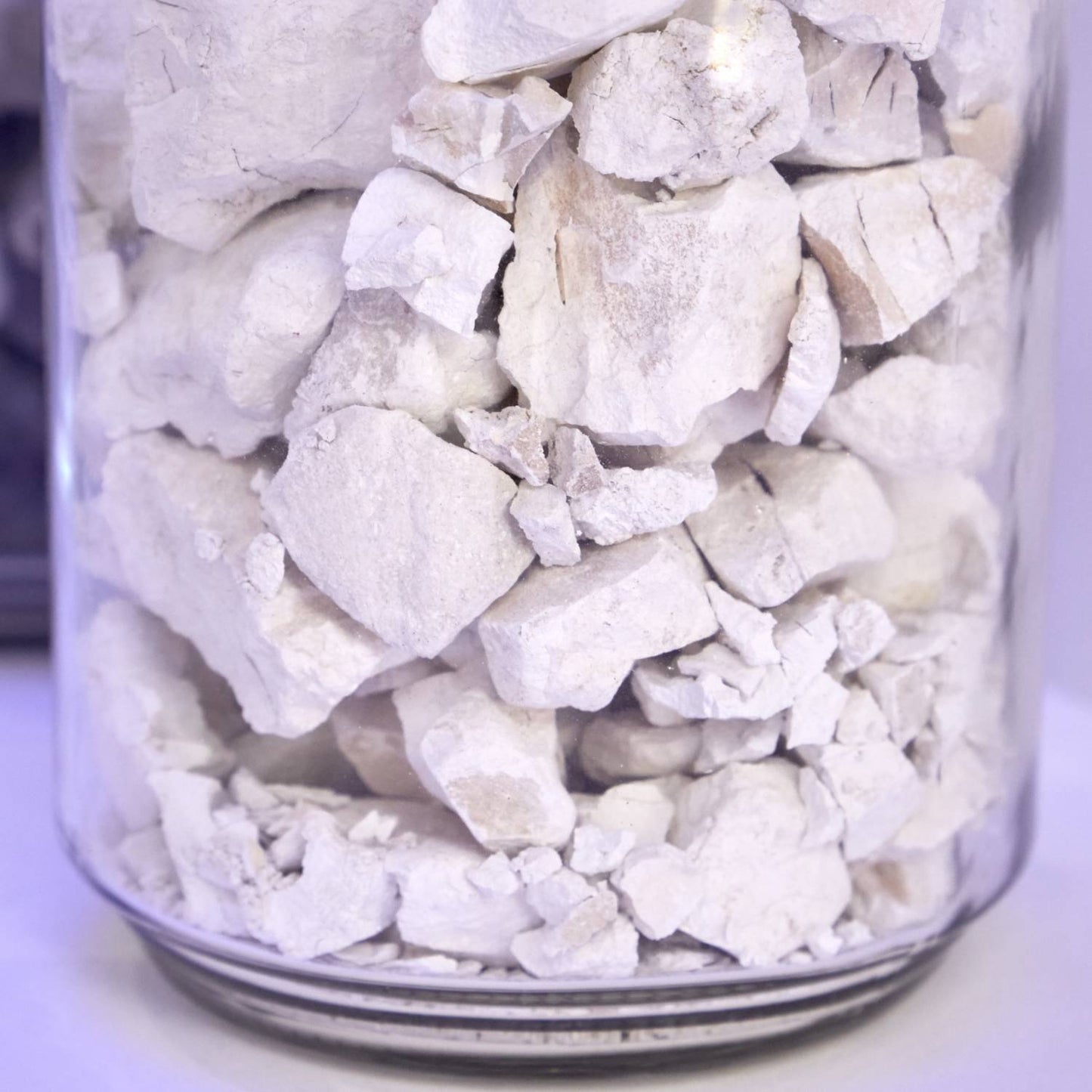 Close-up of rough white calcium carbide chunks stored in a clear container, handcrafted for use in lamps and lighting, parts and accessories, and lamp and lantern fuel collections.