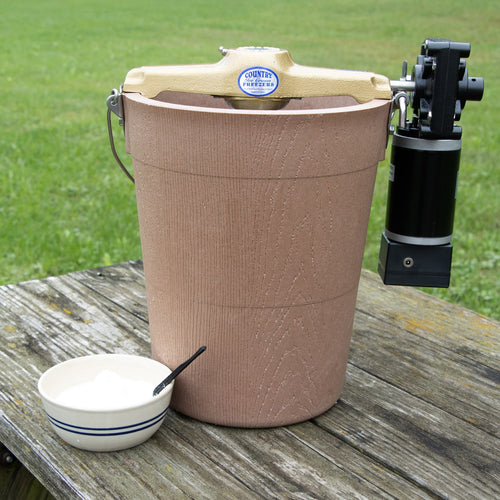 Handcrafted electric ice cream freezer with a poly-insulated bucket and motor, shown on a rustic wooden table outdoors with a bowl, featured in Kitchen & Food and Specialty Equipment collections.