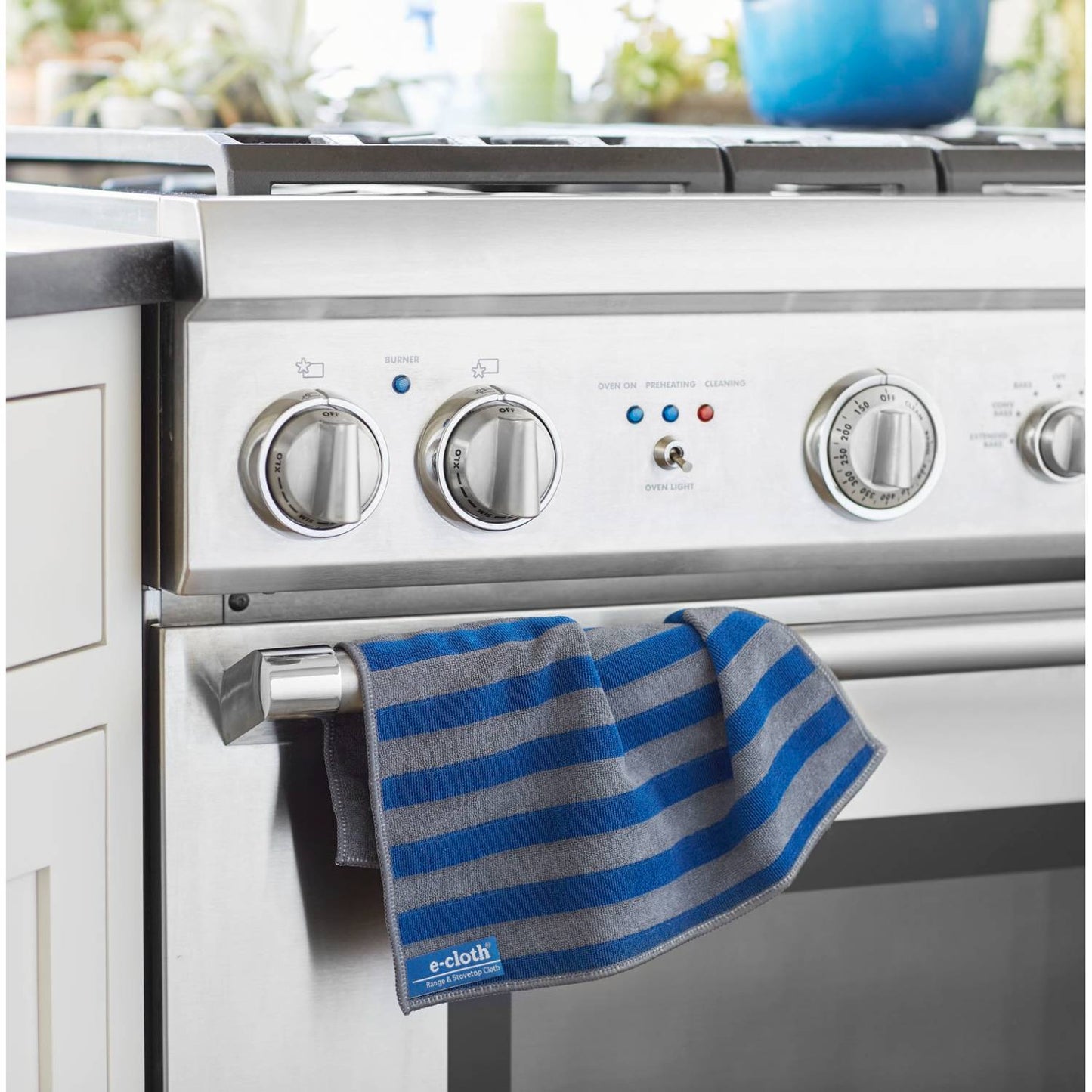 Blue and gray striped microfiber cleaning cloth hanging on a stainless steel oven handle, designed for chemical-free cleaning, ideal for Home & Decor, Household Cleaning, and Best Sellers collections.