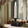 LED candle in a black holder emitting warm white light on a rustic window sill decorated with pinecones and red berries, perfect for Holiday Decor and Home & Decor collections.