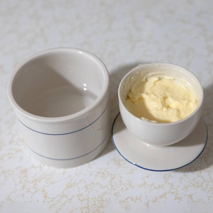 Handcrafted ceramic butter crock with simple blue lines, designed for keeping butter fresh and spreadable without refrigeration, ideal for kitchen, homesteading, and specialty equipment collections.