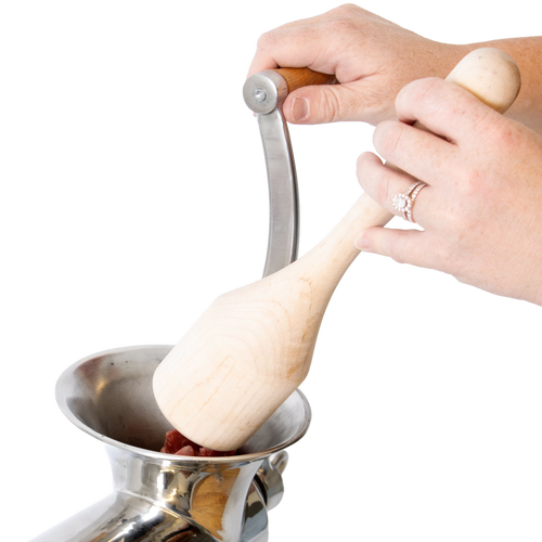 Hands using a smoothly sanded hardwood stumper to safely feed meat into a metal grinder, showcasing handcrafted Amish Made quality in Kitchen & Food and Butchering Supplies collections.