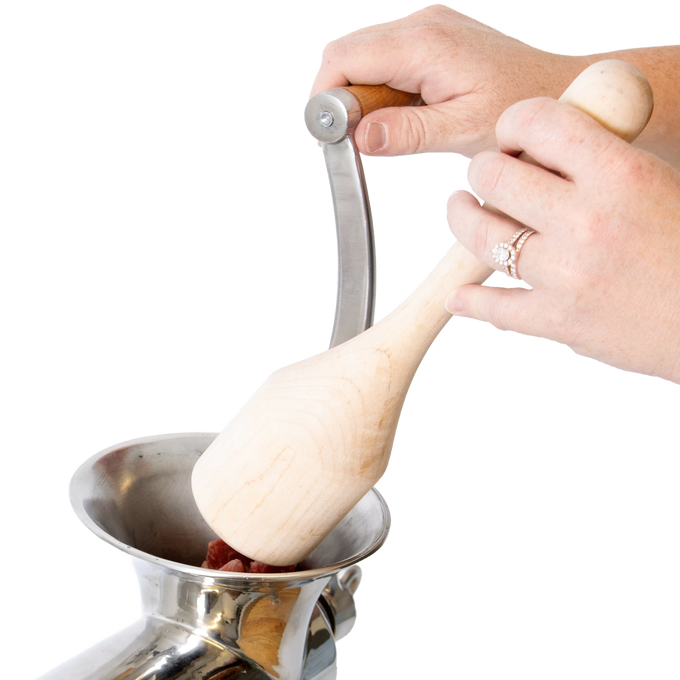 Hands using a smoothly sanded hardwood stumper to safely feed meat into a metal grinder, showcasing handcrafted Amish Made quality in Kitchen & Food and Butchering Supplies collections.
