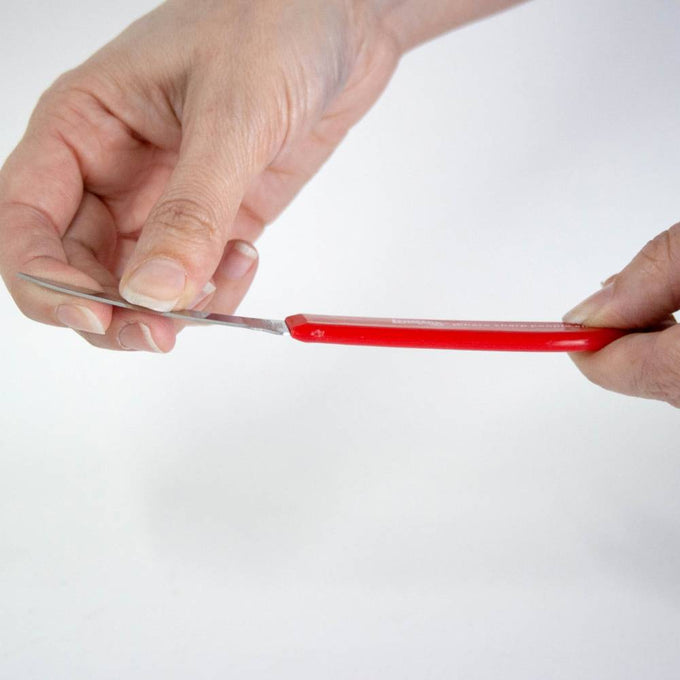 Handcrafted flexible paring knife with a sharp blade and red handle being bent to show flexibility, ideal for precise peeling and coring, featured in Kitchen & Food and Farm, Garden & Tool collections.