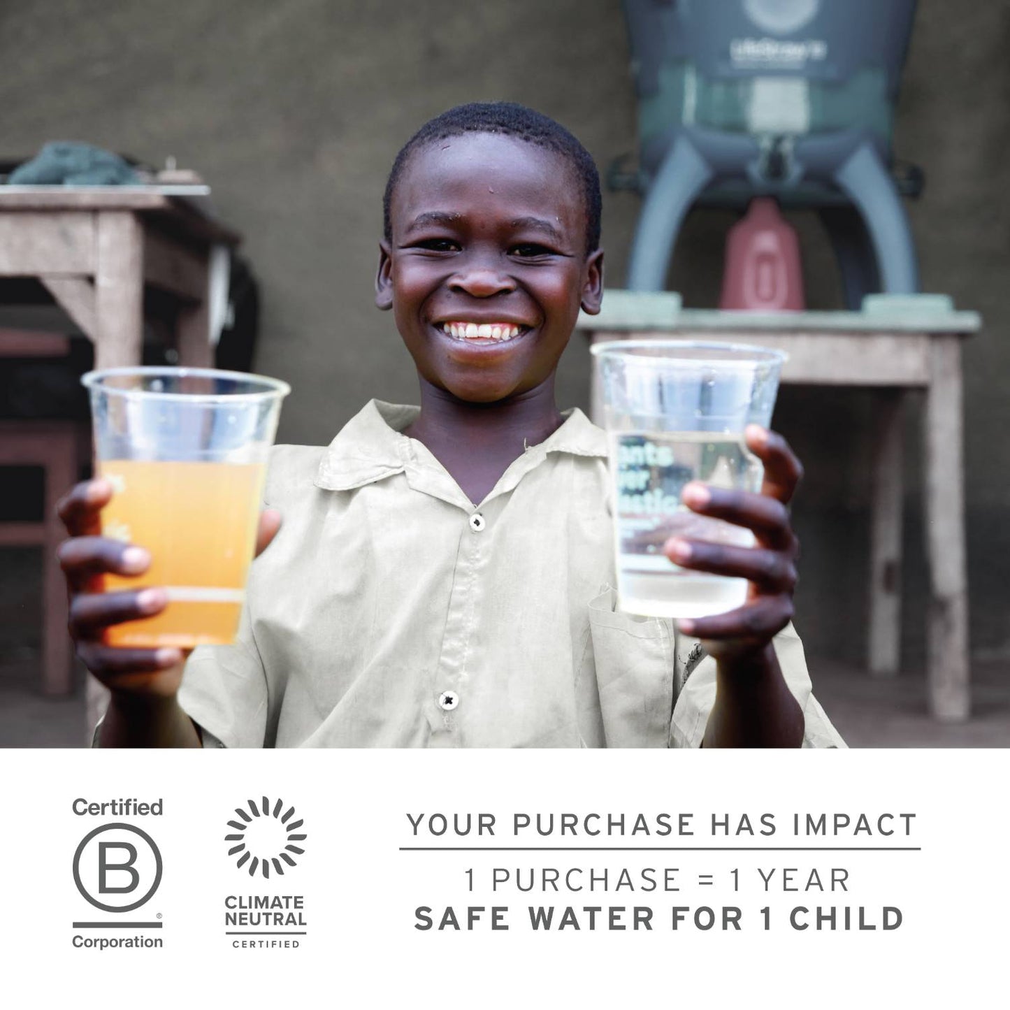 Smiling child holding two plastic cups, one with dirty water and one with clear filtered water, demonstrating safe water access from a water filter in an outdoor setting.