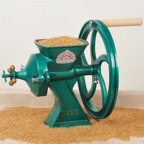 Cast iron grain mill with a green finish and wooden handle, grinding whole grains in a kitchen setting, featured in baking supplies and cookware collections.