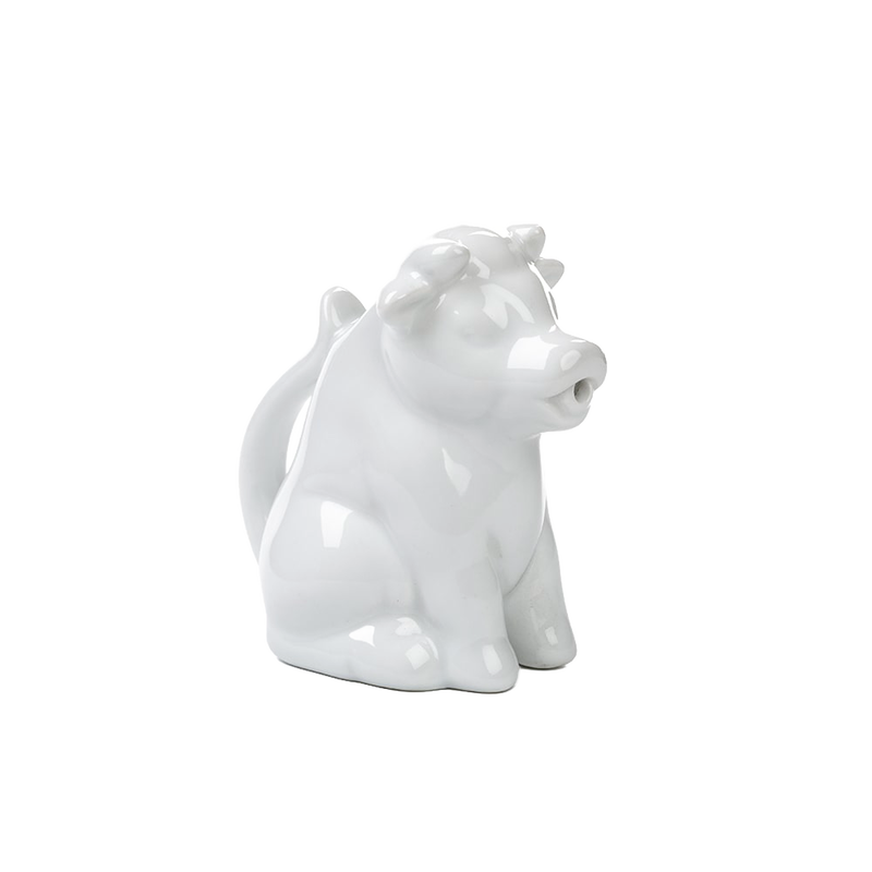 Glossy white porcelain creamer shaped like a sitting cow with a tail handle and pouring-spout mouth, handcrafted and perfect for Kitchen & Food, Brewing Coffee and Tea, Dinnerware collections.