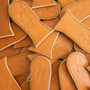 Collection of handcrafted vegetable-tanned leather skillet handle covers embossed with a vintage wagon design, heat-resistant and made in USA, perfect for kitchen and cast iron cookware.